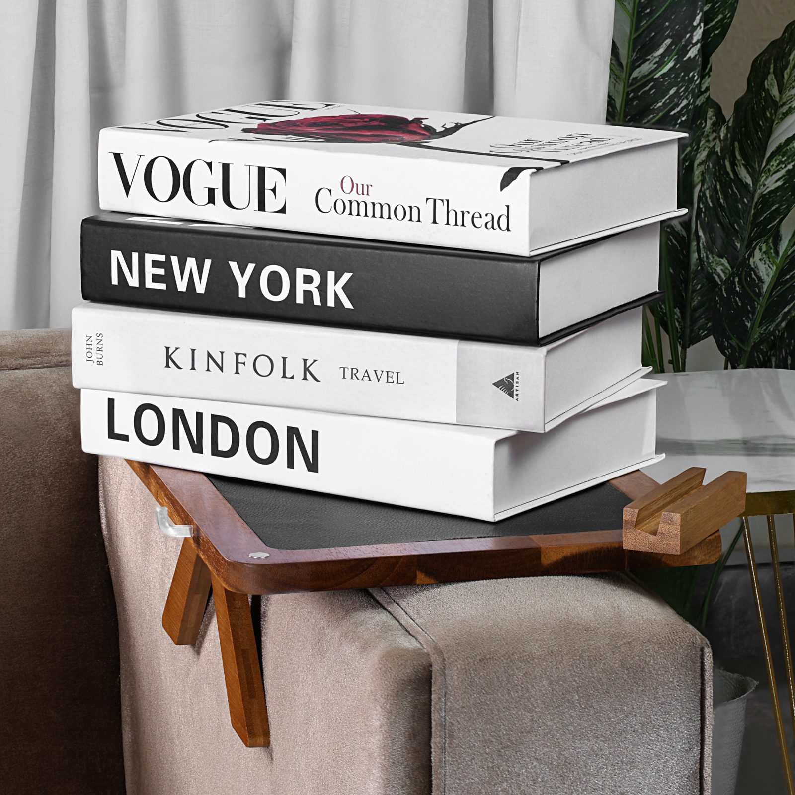 A stack of hardcover books resting on the acacia couch arm tray to demonstrate stability