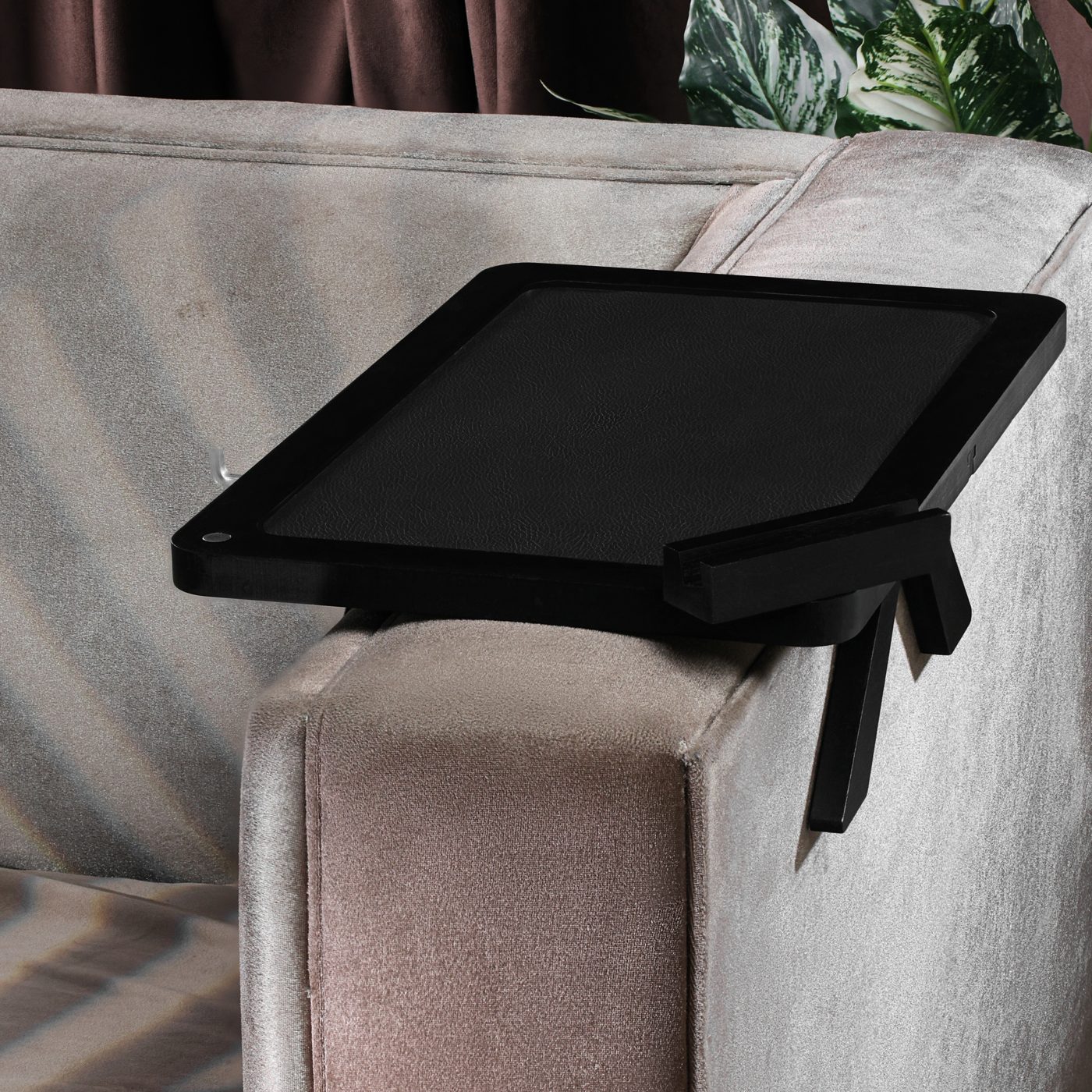 Black couch arm tray clamped on a sofa armrest