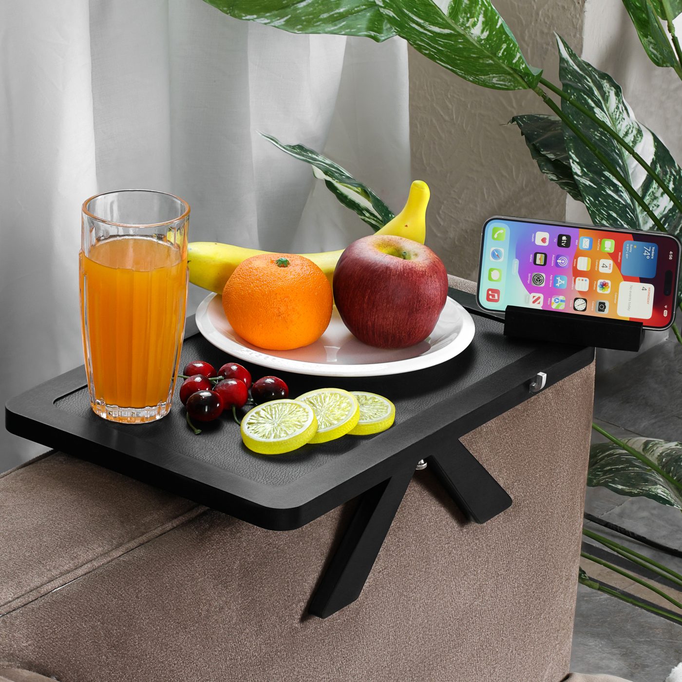 Black tray holding breakfast, juice, and a phone