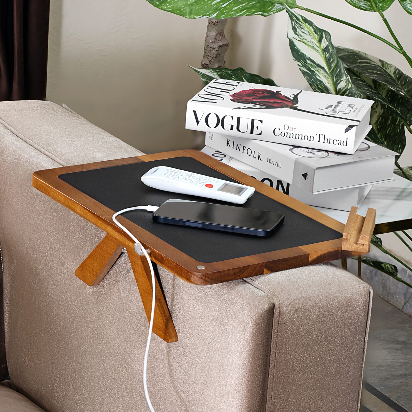 Acacia tray with phone charging through the cable groove and books stacked behind