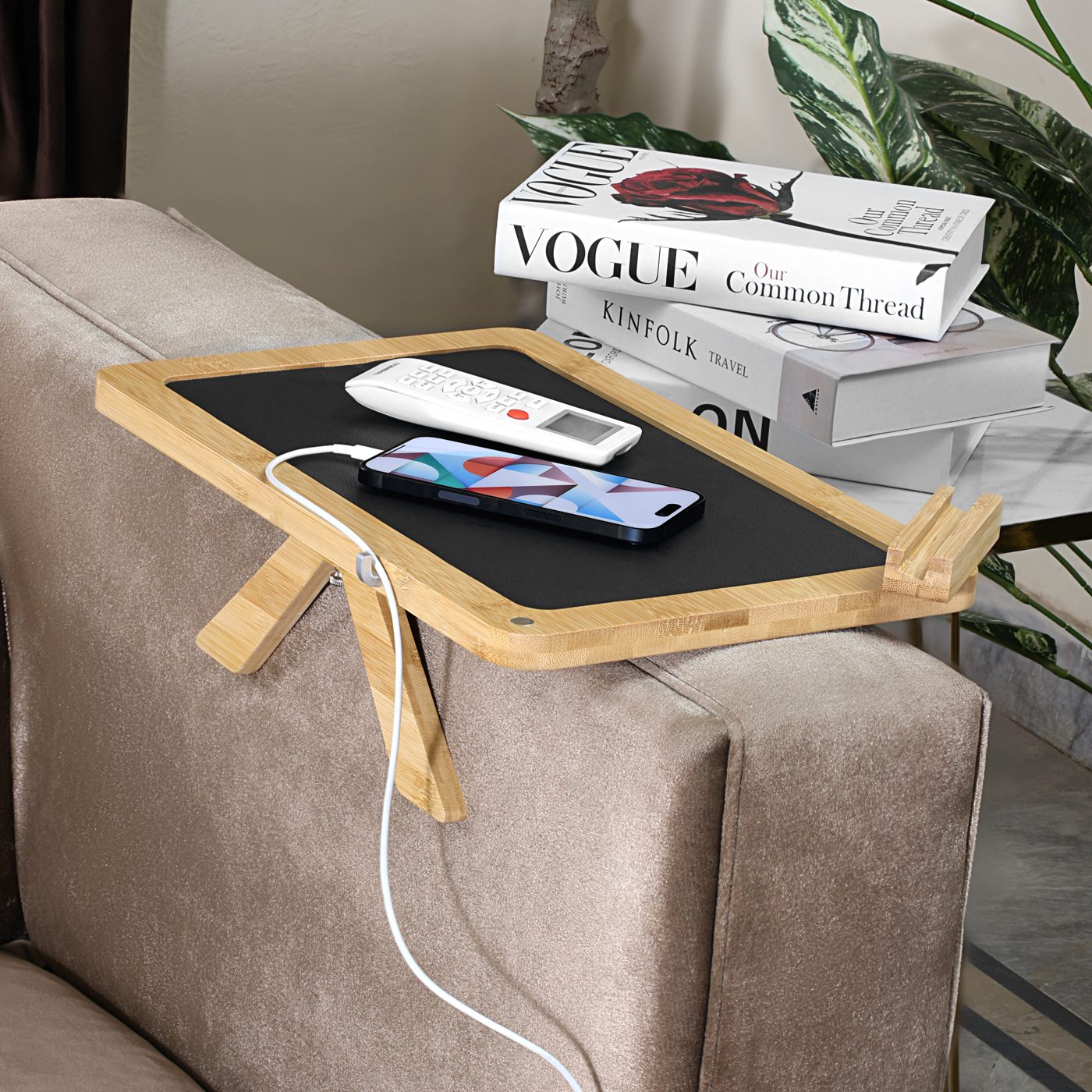 Bamboo tray with phone charging through the cable groove and books stacked behind