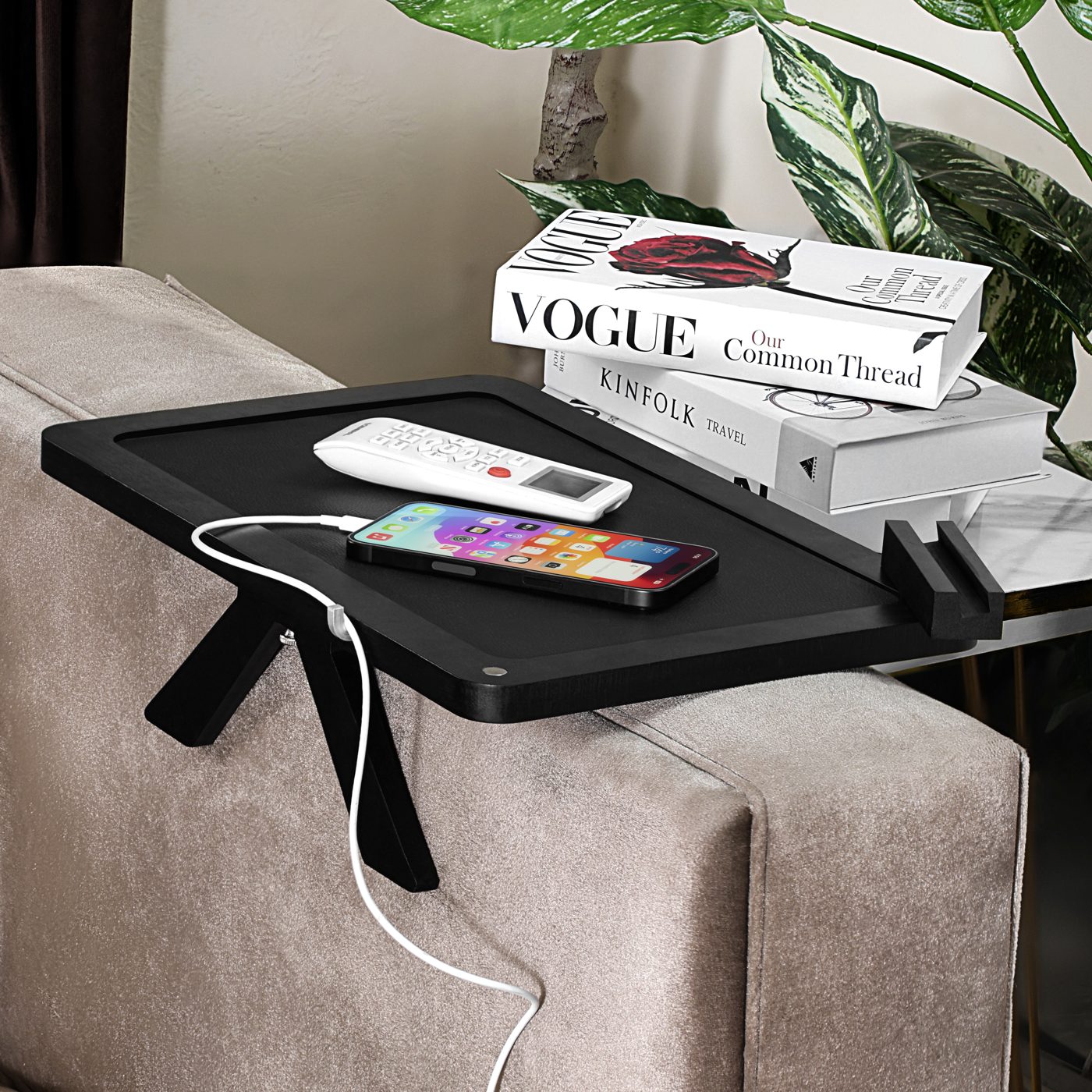 Black tray with phone charging through the cable groove and books stacked behind
